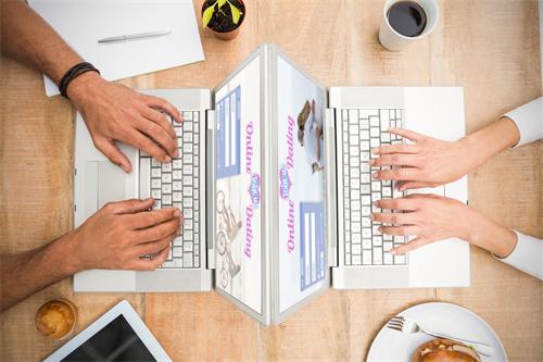 Two people using laptops with online dating websites open
