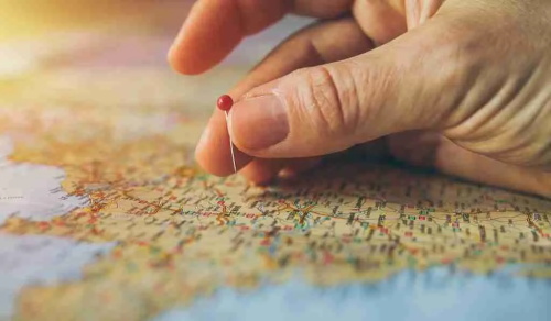 Hand placing red pin on map