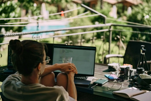 Woman working on laptop outdoors with cameras nearby